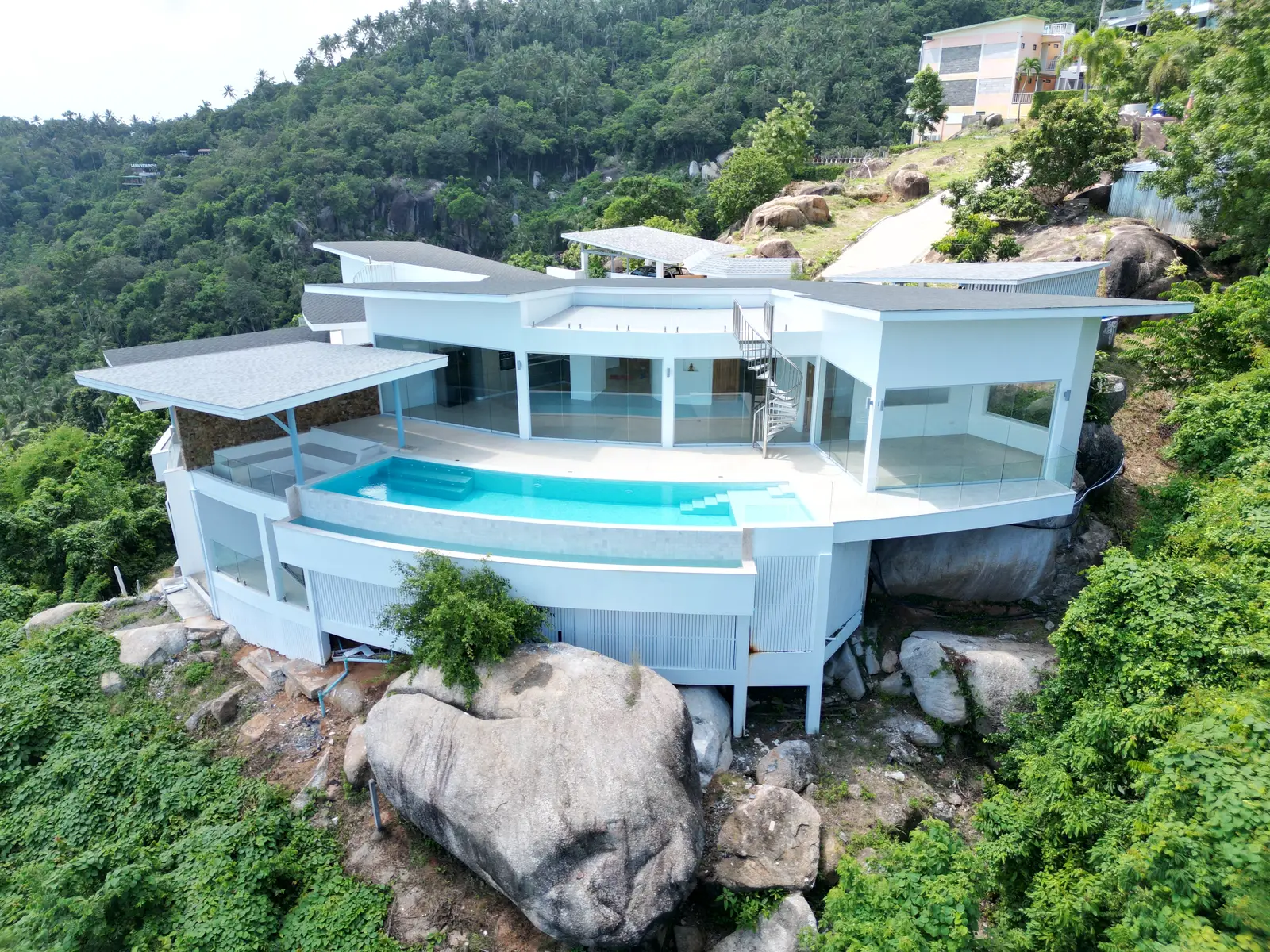 Villa Emerald from the front — curved salt-water infinity pool cantilevered over granite boulders